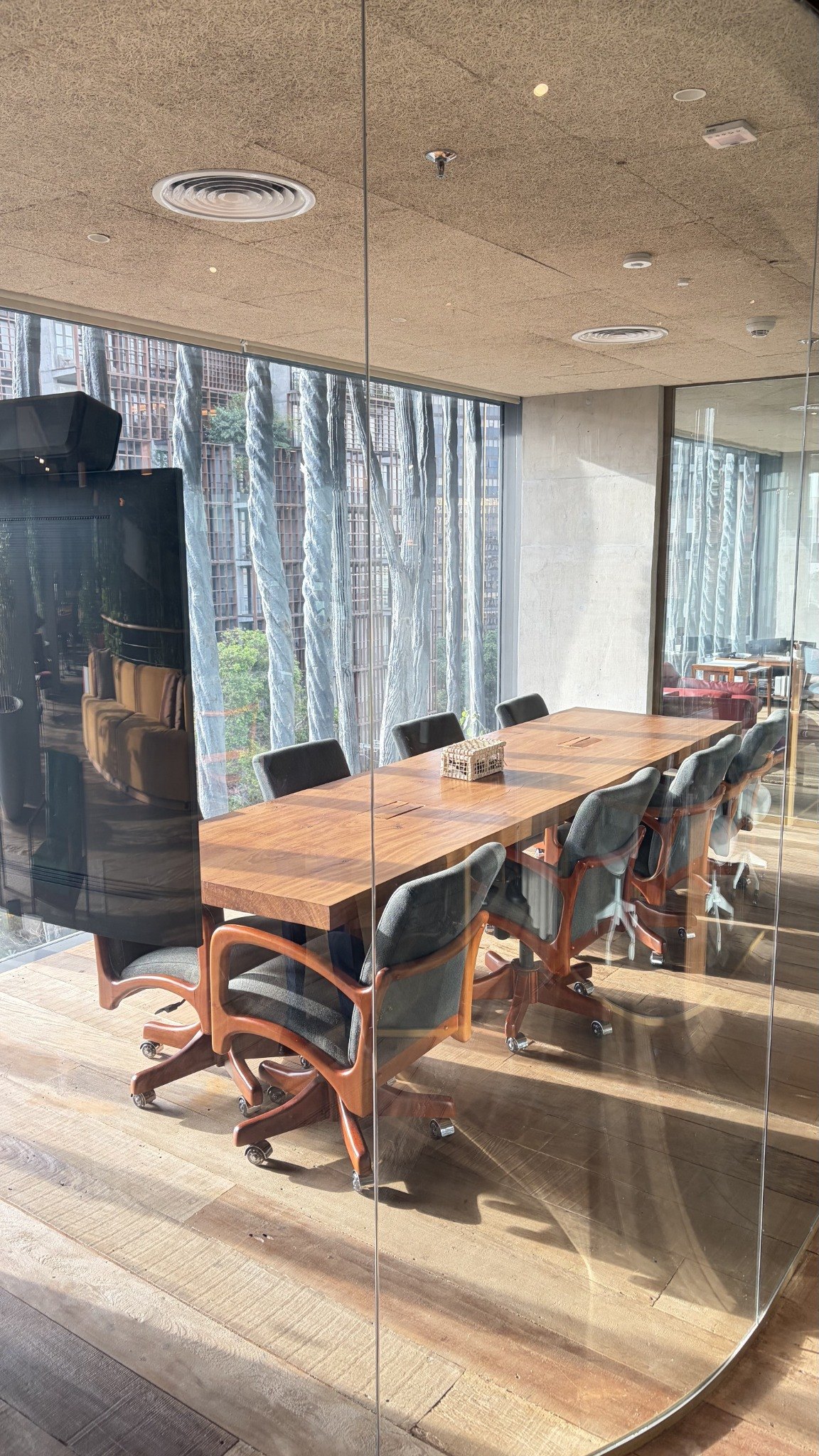 Sala de reuniões do escritório, com mesa de madeira e janelas voltadas para os jardins